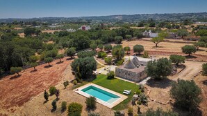 An aerial view of a property with a swimming pool, stone buildings, and surrounding greenery. - TD Trullo Buenavista Stunning Valley Views W/pool (Ostuni)