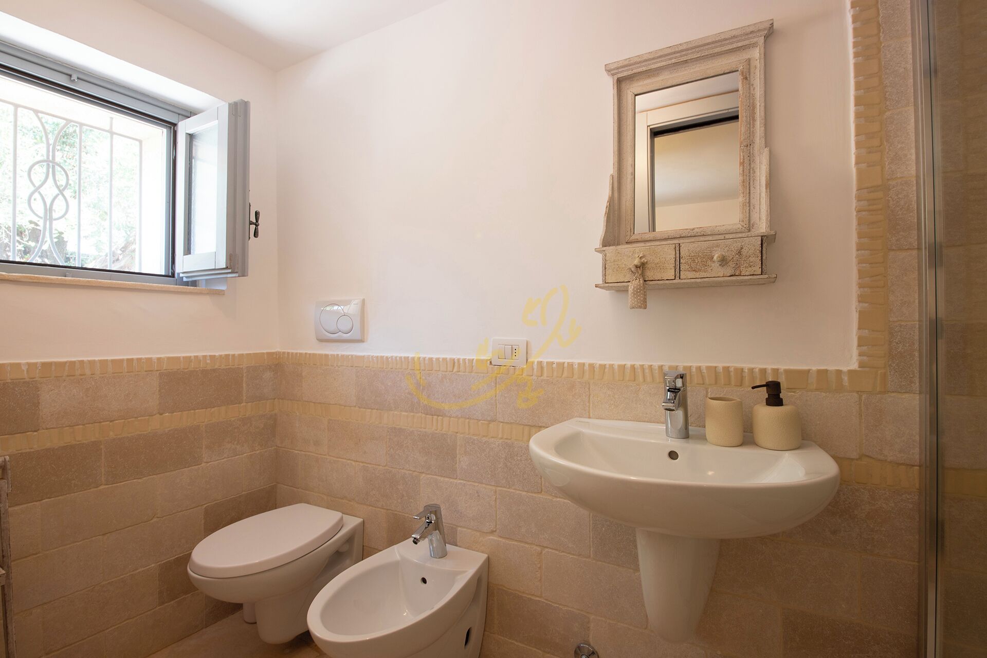 A bathroom with a toilet, bidet, sink, and a mirror above the sink.