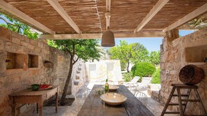 Un espace de restauration extérieur de style rustique, avec des murs en pierre, des meubles en bois et un luminaire suspendu.