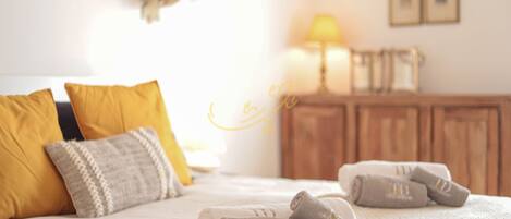 Una cama bien hecha con toallas enrolladas, un armario de madera y una lámpara en una habitación de hotel.