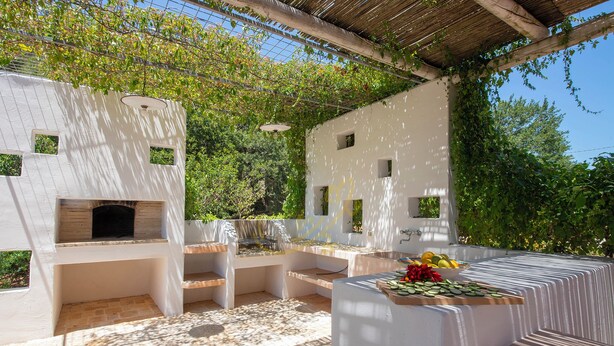 An outdoor patio with a built-in grill, seating area, and a table with fruits and vegetables. - TD Casale Belladinotte Poolside Country Bliss (Ceglie Messapica)