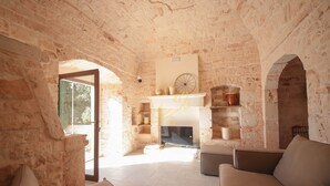 A stone-walled room with a fireplace, a sofa, and a coffee table. - TD Torretta San Procopio Stone House With Pool (Castellana Grotte)