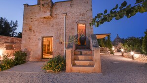 A stone building with a staircase leading to an entrance, surrounded by gravel and plants. - TD Torretta San Procopio Stone House With Pool (Castellana Grotte)