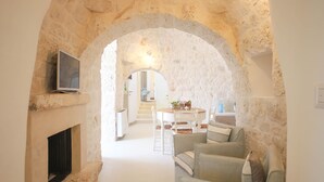 A cozy living area with a stone archway, a fireplace, and a seating area with a table and chairs. - TD Lamiamola Stylish Trulli & Lamie With Pool (Ostuni)