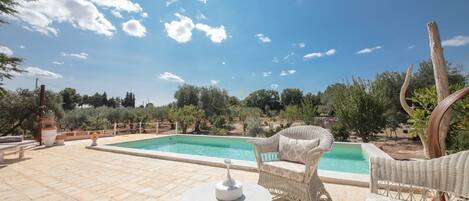 A pool area with wicker furniture and a clear blue sky.