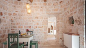 Habitación con paredes de piedra, una mesa de comedor, sillas y un radiador.