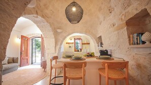 A rustic kitchen with stone walls, a central island with bar stools, and a hanging light fixture. - TD Trulli Altura With Pool & Stunning Sunsets (Martina Franca)
