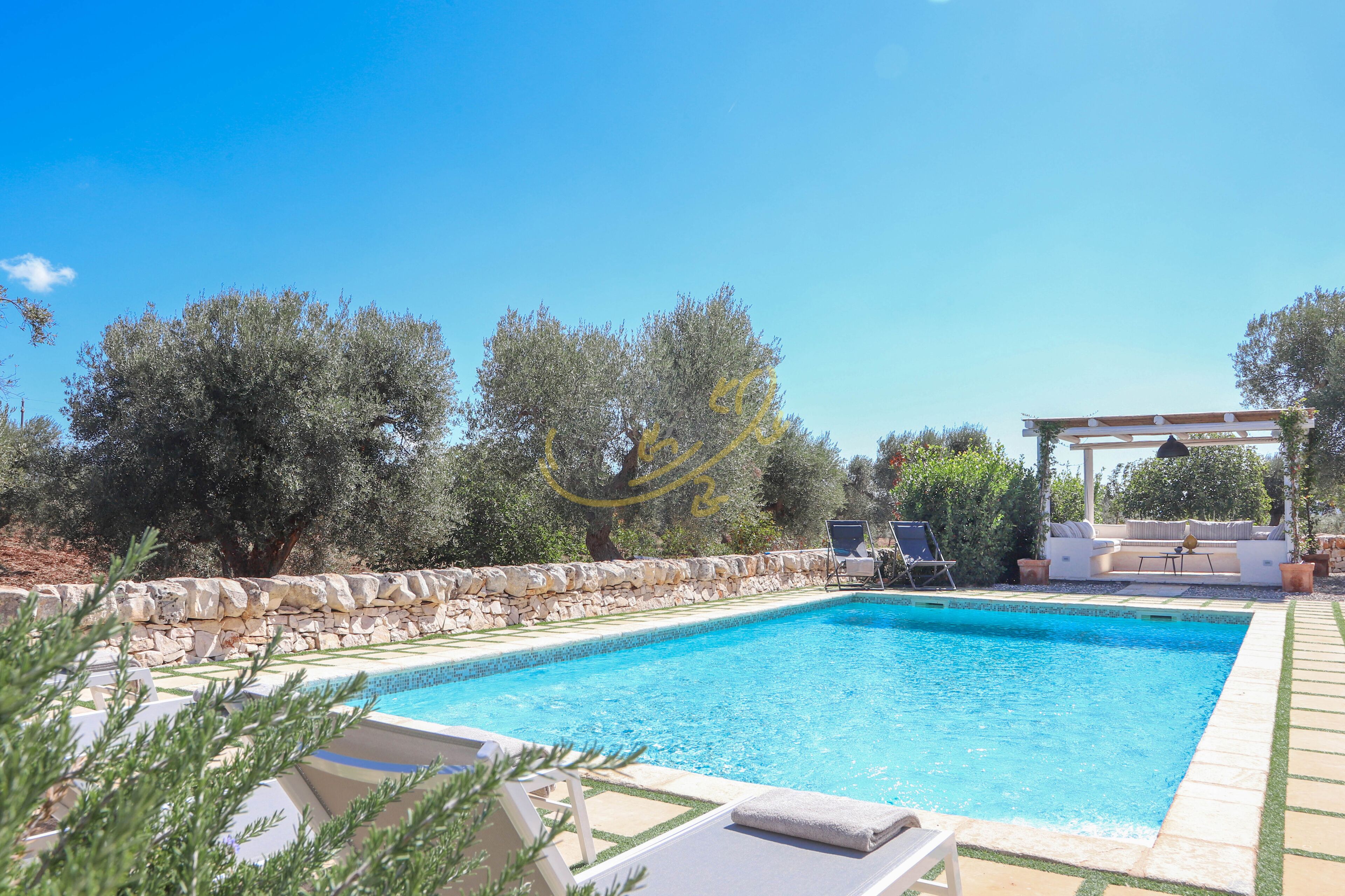 A swimming pool with lounge chairs and a pergola.
