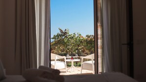 An open room with a view of a patio, a table with two chairs, and a bed with a white comforter. - TD Tenuta Donna Madia Sea View Pool Over Vineyard (Monopoli)