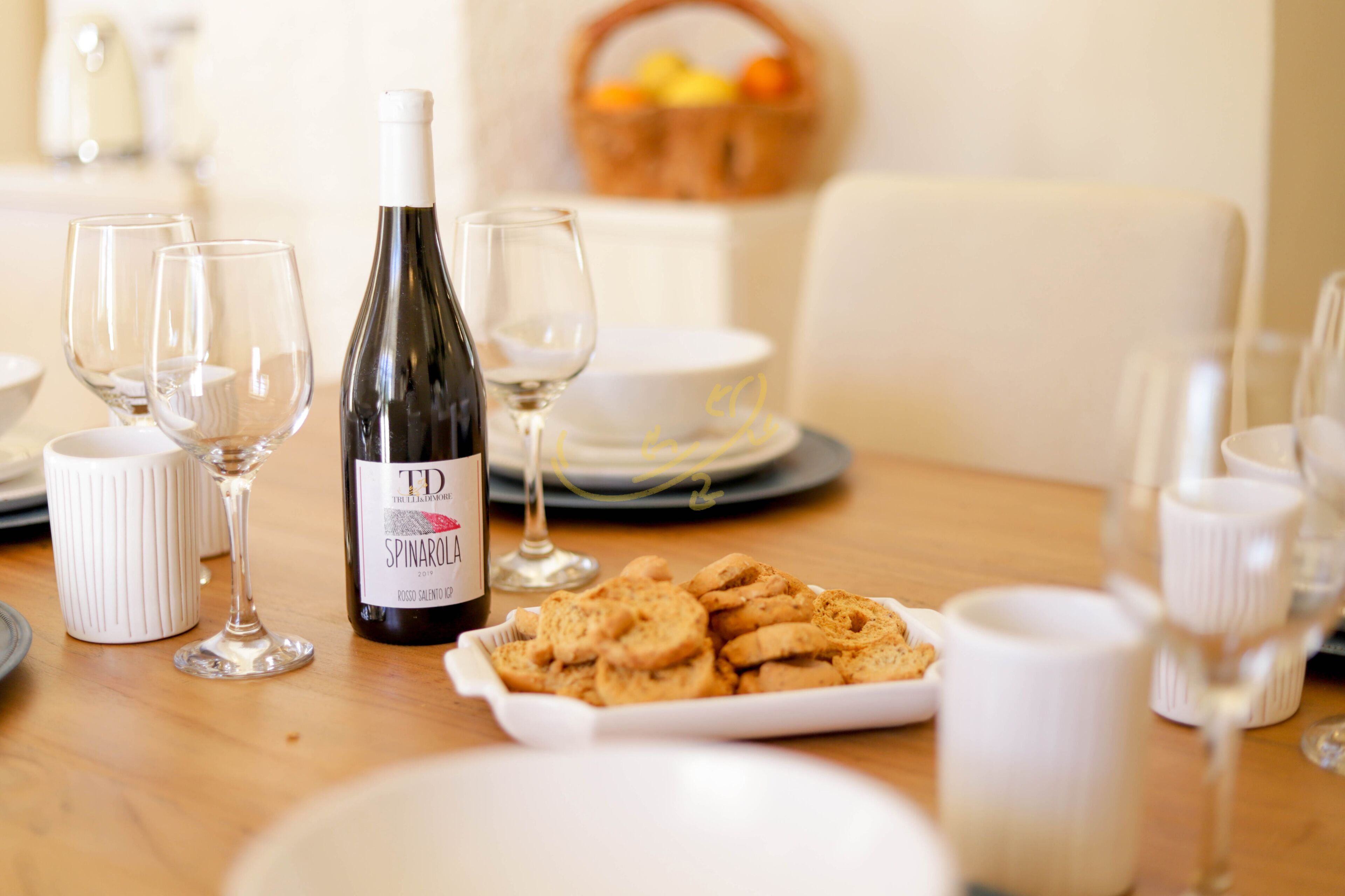 A dining table set with wine glasses, a bottle of TD Spinarolo wine, and a plate of cookies.