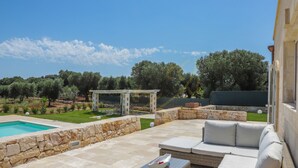 A patio with a stone wall, a pool, and outdoor furniture. - TD Villa Coco Countryside Villa Near Ostuni (Ostuni)