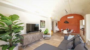 A modern living room with a large sofa, a TV, and a dining area with a table and chairs. - TD Villa Coco Countryside Villa Near Ostuni (Ostuni)