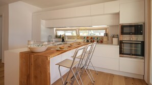 A modern kitchen with a wooden island, white cabinetry, and stainless steel appliances.