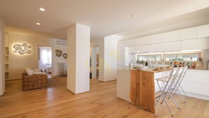 A modern kitchen with a wooden island, white cabinetry, and a dining area with chairs.