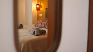 Een hotelkamer met een bed, een gestreept kussen en opgerolde handdoeken.