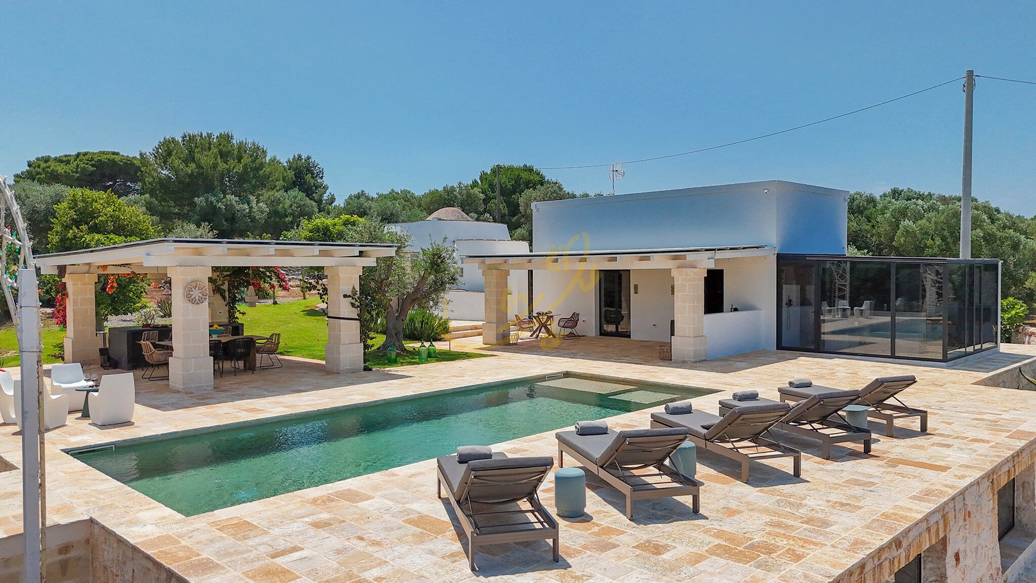 A modern outdoor pool area with lounge chairs and a covered seating area.