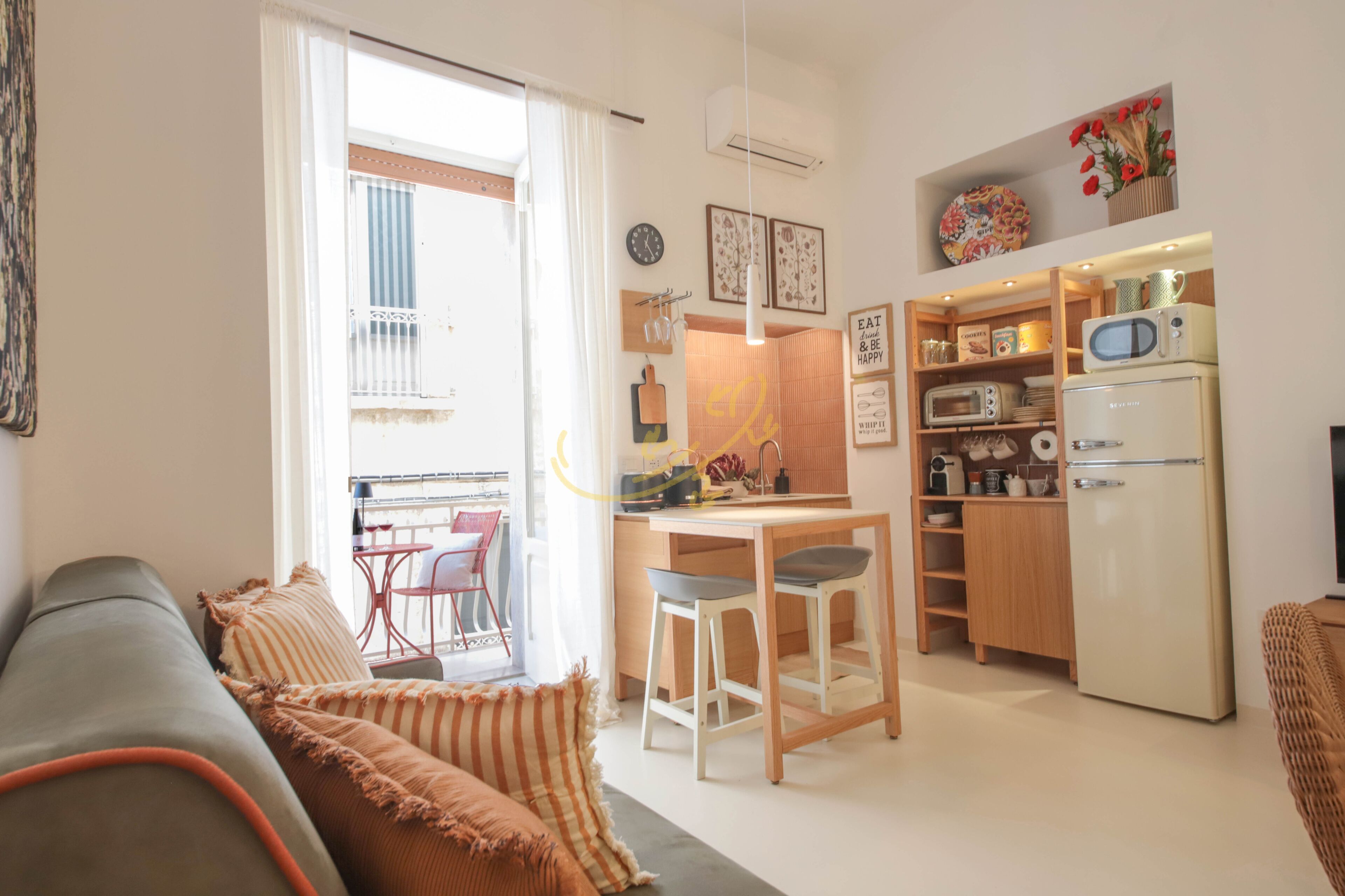 Ett kompakt bostadsutrymme med ett litet kök, en matplats och en soffa.