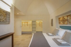 A hotel room with a bed, a bedside table, a headboard, a wall-mounted artwork, and a door leading to a bathroom.