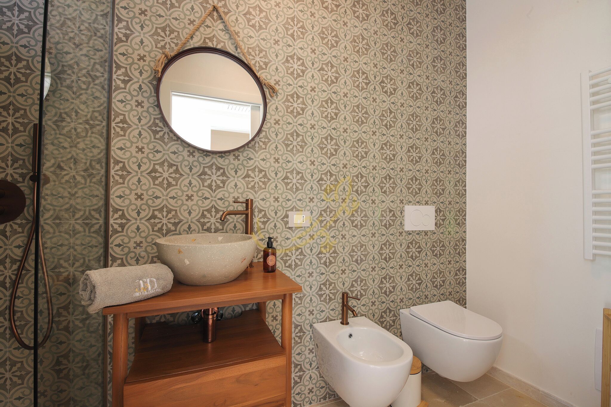 A bathroom with a wooden vanity, a large bowl sink, a bidet, and a mirror.