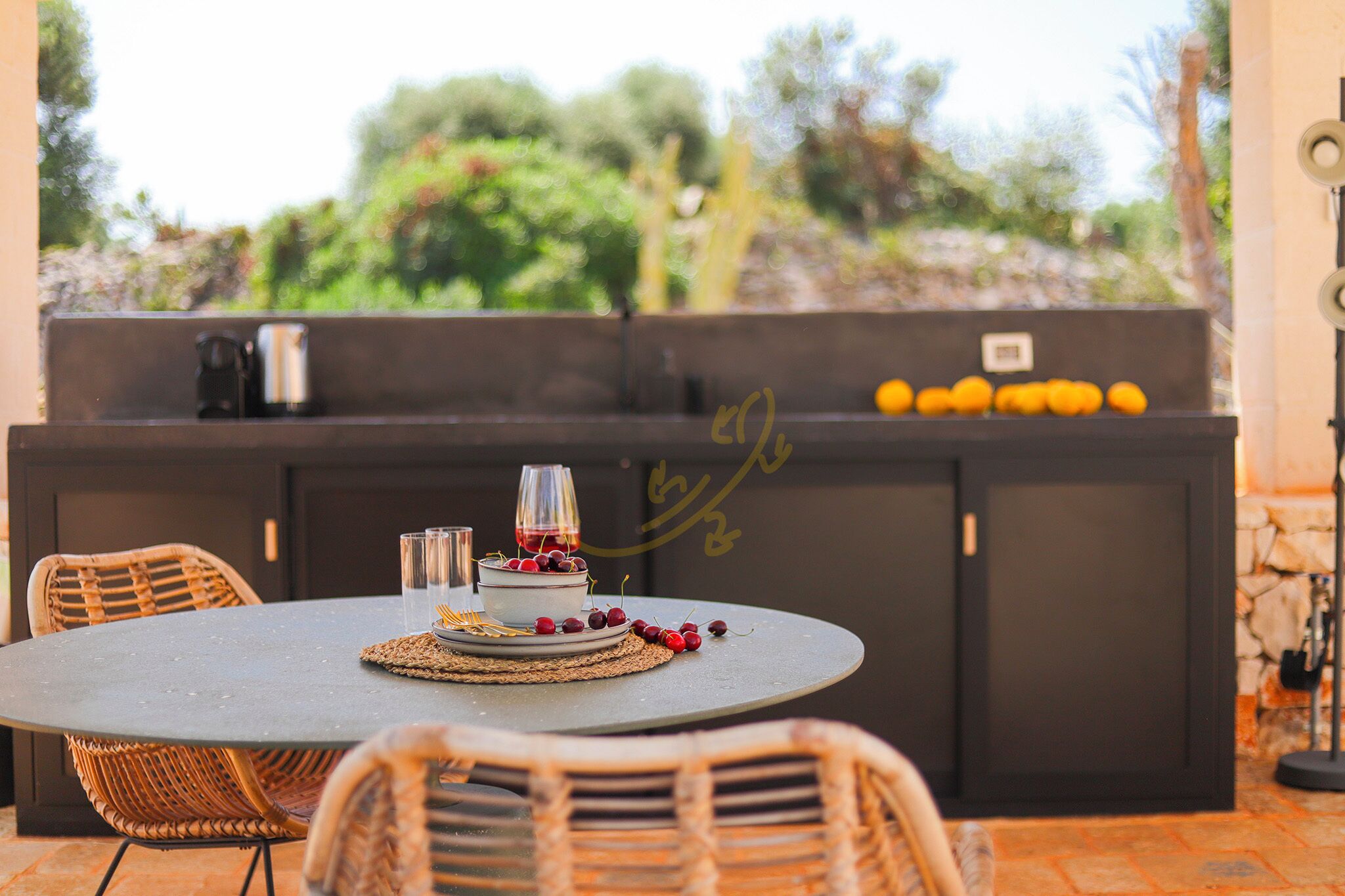 An outdoor dining area with wicker chairs, a round table, and a built-in barbecue station.