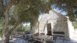 An outdoor dining area with a stone building, a table, chairs, and a bench. - TD Trullo Morena Charming Trullo,stunning Sunsets (Monopoli)