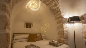 A cozy room with a bed, a lamp, and a wall with a circular design. - TD Trullo Morena Charming Trullo,stunning Sunsets (Monopoli)