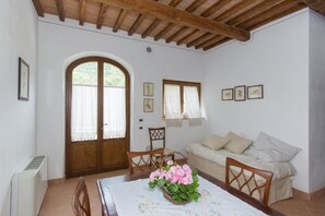 Quarto com teto de madeira, mesa de jantar com cadeiras, sofá e porta com janela.