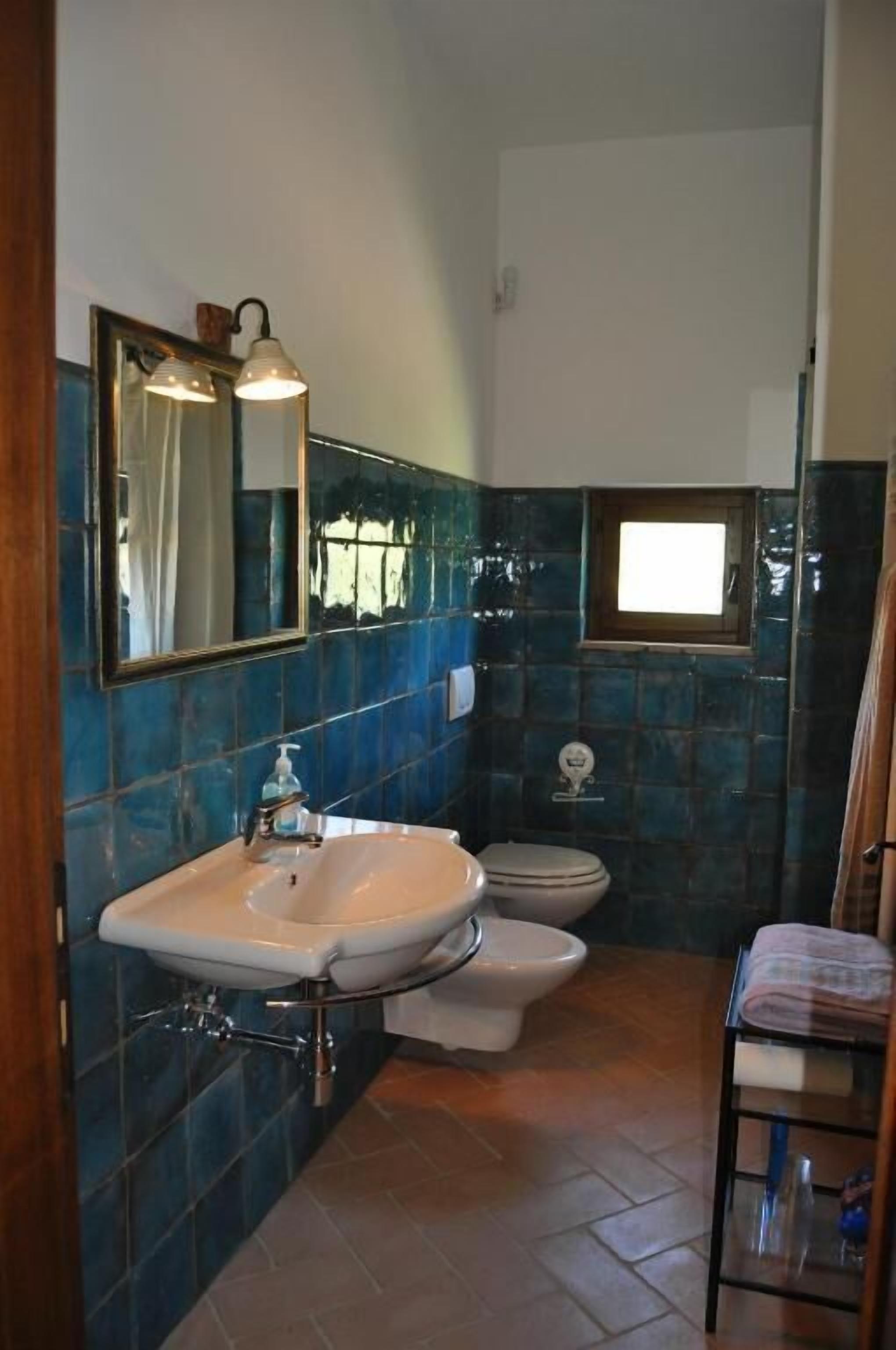 A bathroom with a sink, toilet, and mirror.