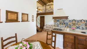A dining area with wooden chairs, a table with a lace tablecloth, and a staircase leading to an upper level. - Agriturismo Il Borgo di San Michele (Terni)