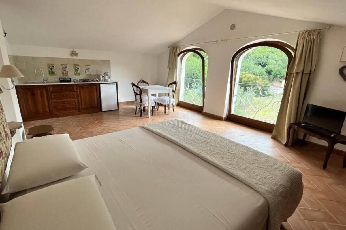 A bedroom with a large bed, a desk, and a view of the outdoors.