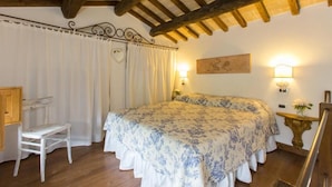 A bedroom with a bed, a chair, a desk, and a painting on the wall. - Agriturismo Il Borgo di San Michele (Terni)
