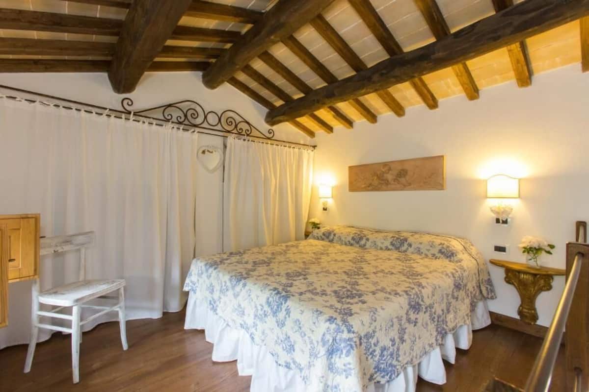 A bedroom with a bed, a chair, a desk, and a painting on the wall.