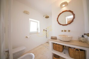 Un baño con inodoro, lavamanos con un espejo grande, ducha y ventana.