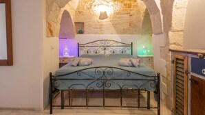 Ein Bett in einem Zimmer mit Steinwänden und einer gewölbten Decke.