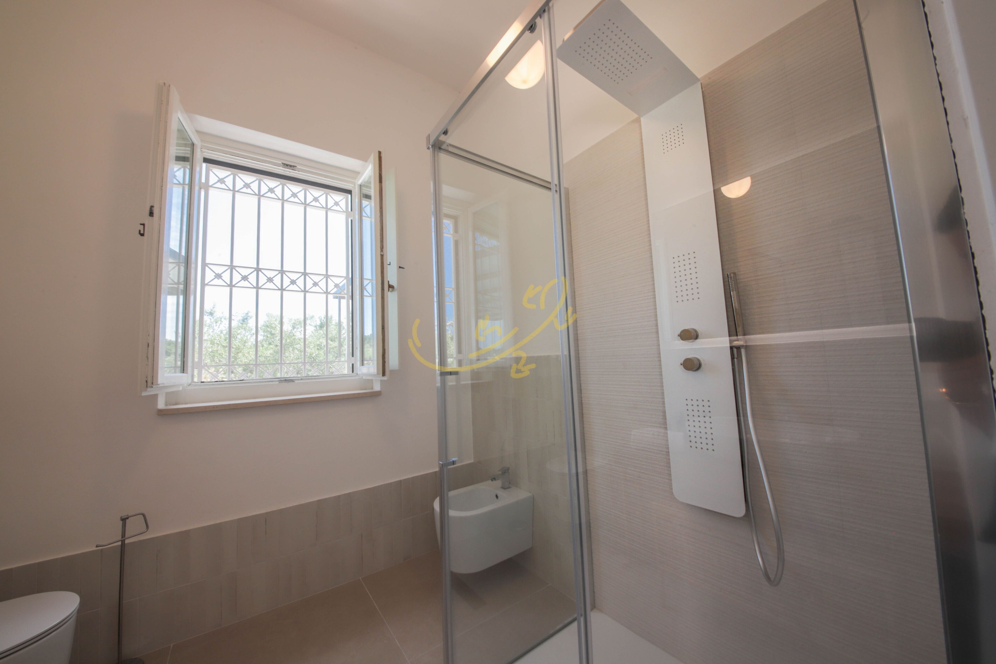 A modern bathroom with a glass shower enclosure, a toilet, and a window.
