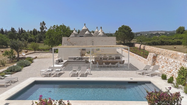 A poolside area with a pool, lounge chairs, a dining area, and a stone wall. - TD I Coni di Pinurè Trulli With Scenic Valley .. (Martina Franca)