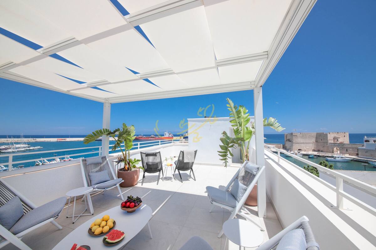 Ein Balkon mit weißer Möbel, einer Obstschale und Topfpflanzen.