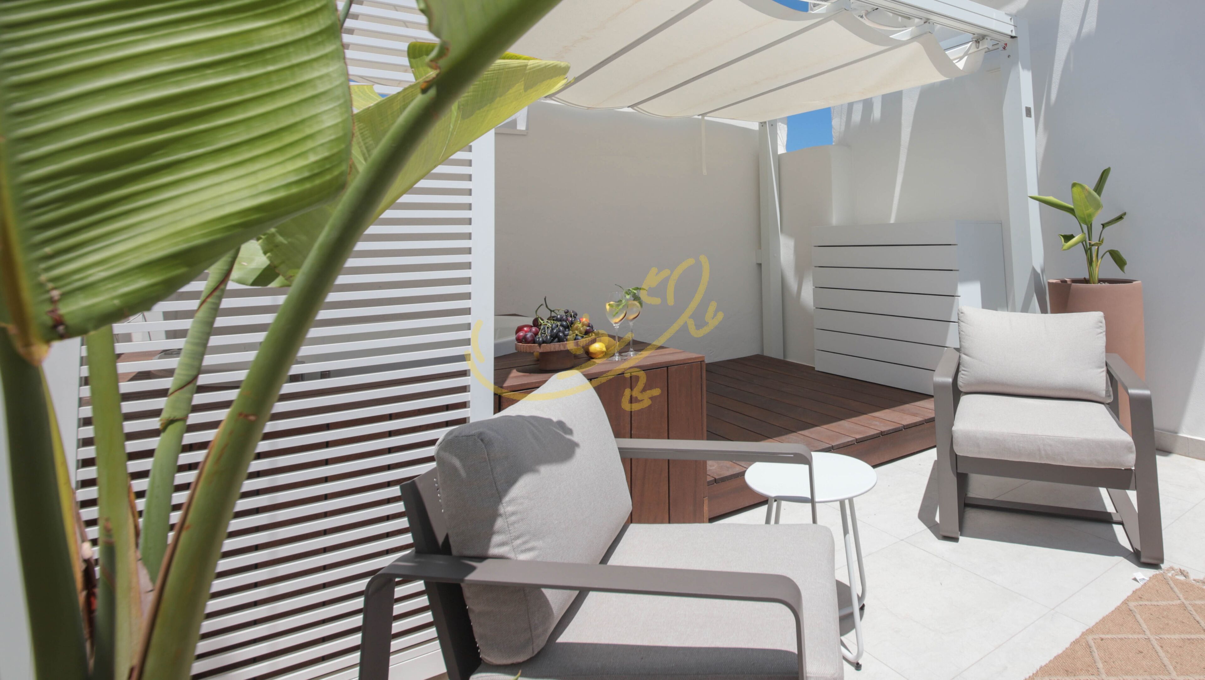A modern outdoor seating area with a wooden table, two chairs, and a potted plant.