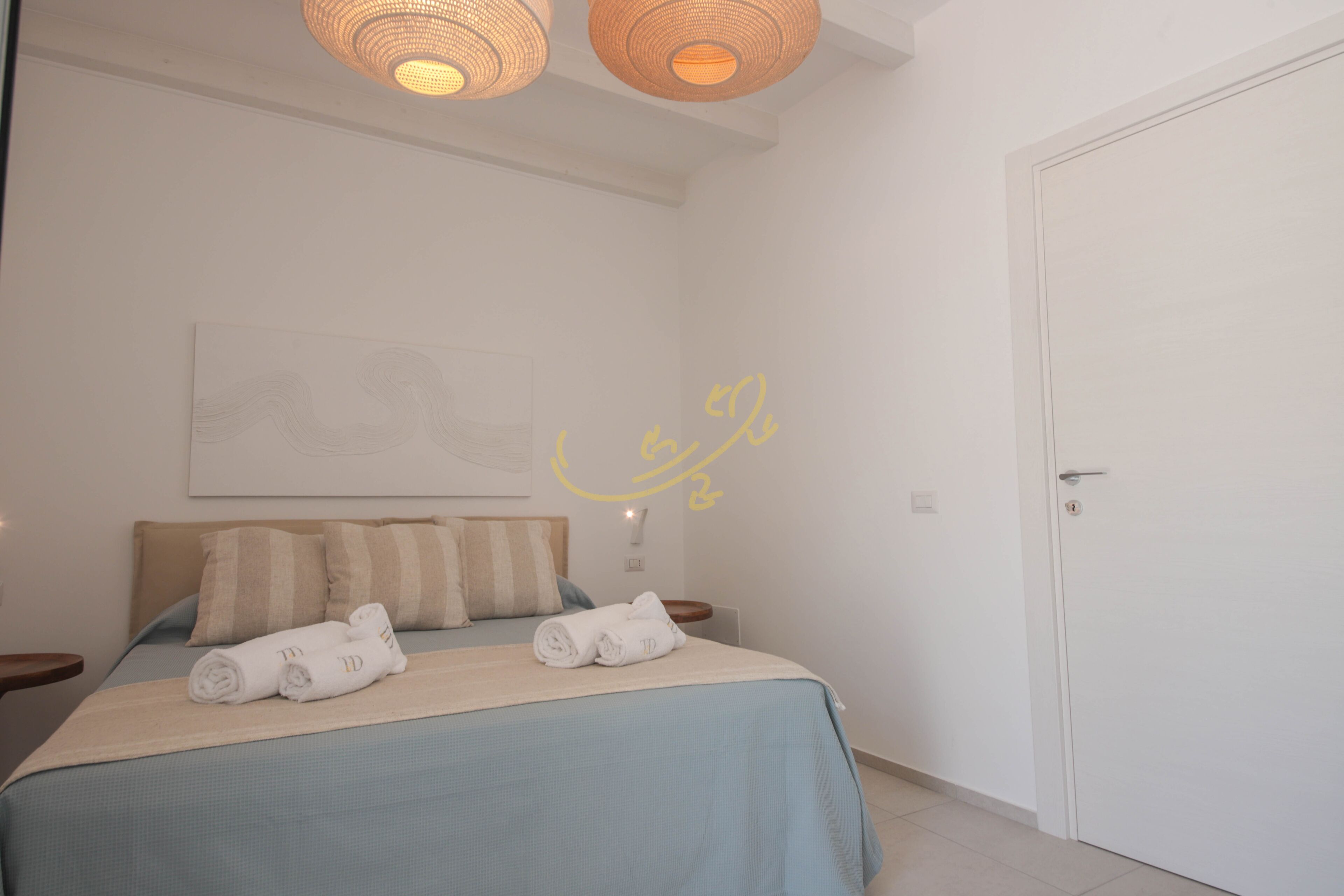 Un dormitorio con cama, almohadas y toallas enrolladas.