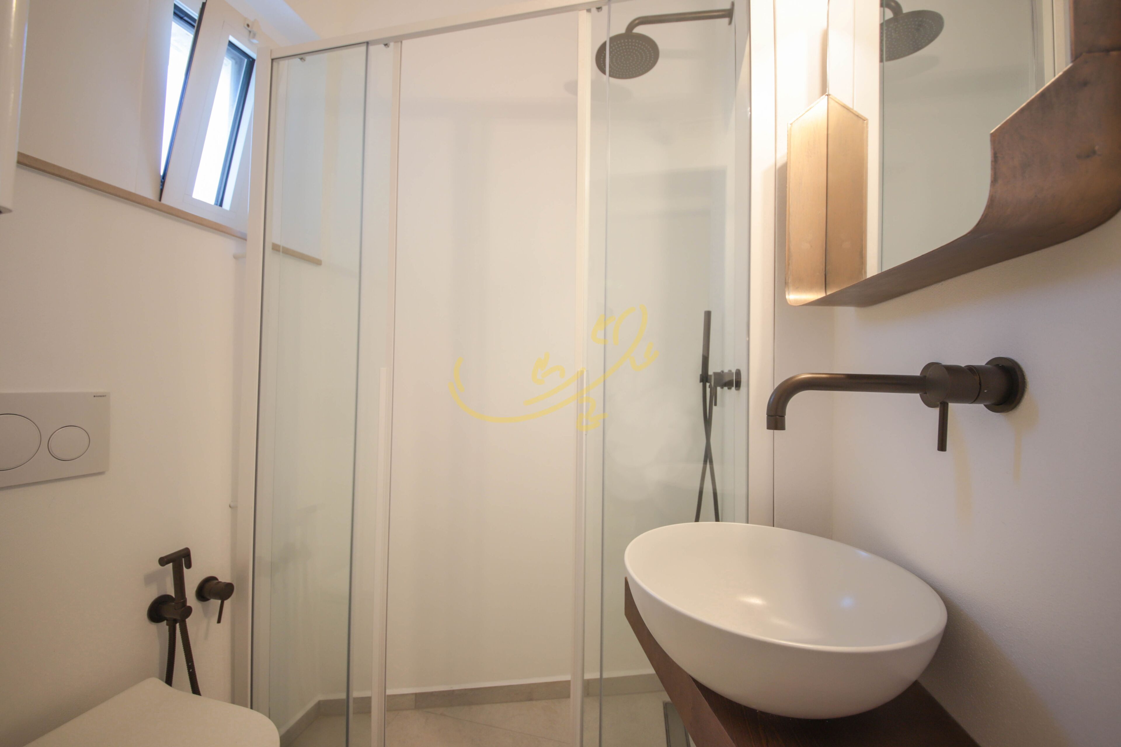 Ein modernes Badezimmer mit einer Duschkabine aus Glas, einem weißen Waschbecken und einer Holzausstattung.