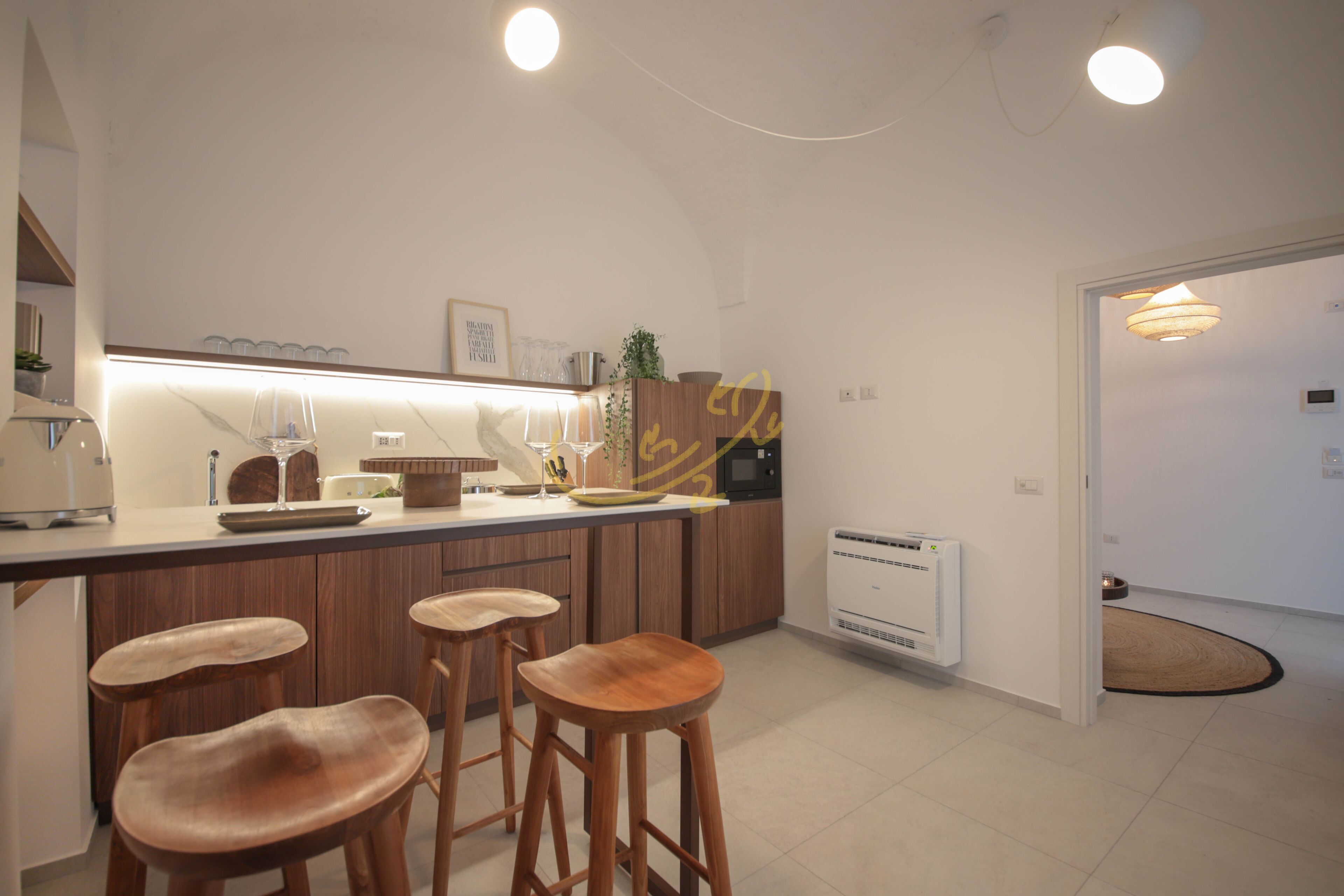 A modern kitchen with wooden bar stools, a built-in oven, and a white countertop.
