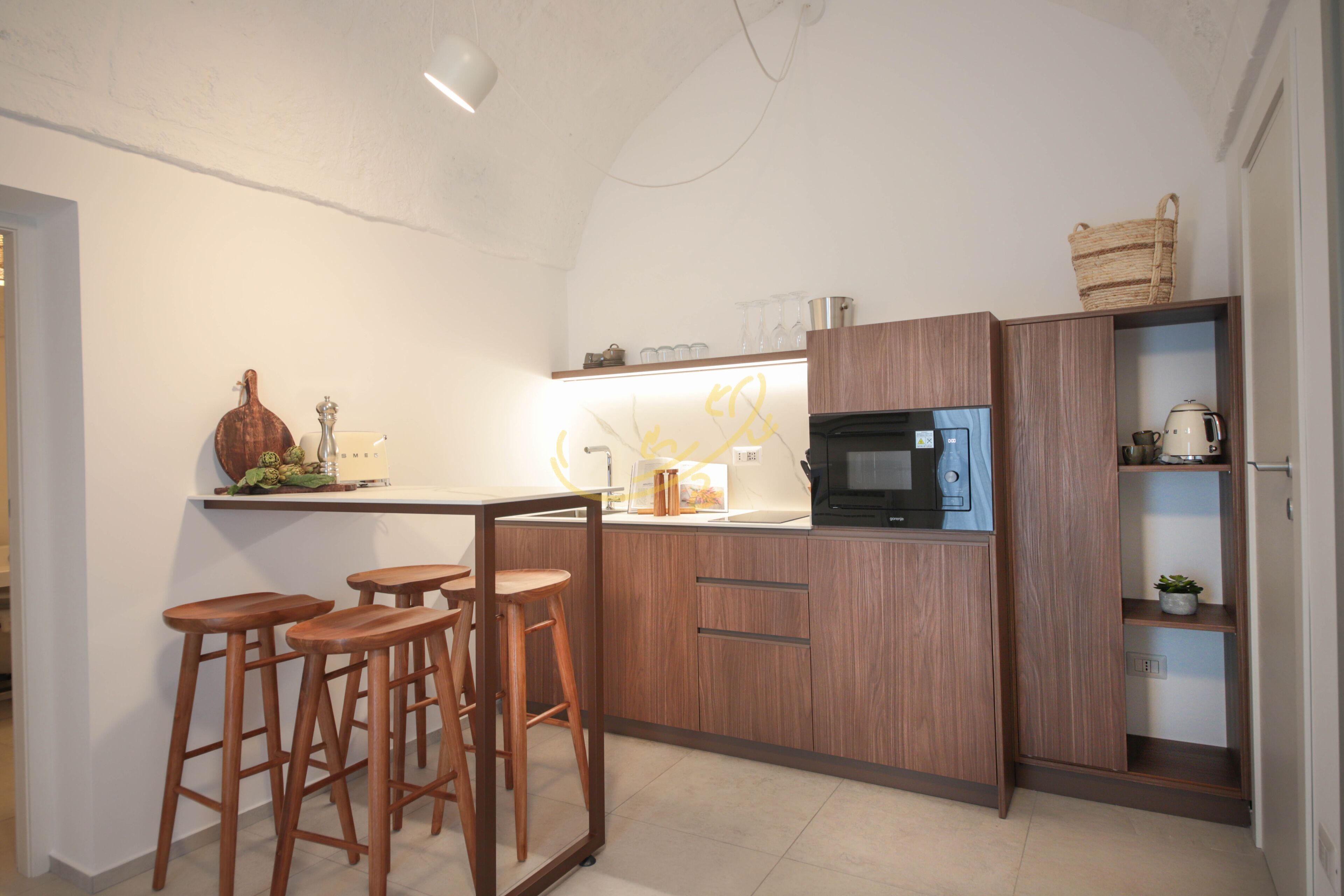 Una cocina moderna con armarios de madera, un microondas y taburetes de bar.