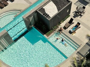 A pool area with a separate section for adults and children, lounge chairs, and a seating area with tables. - Oracle Skyview | Luxury 26th Floor Ocean Escape (Gold Coast)