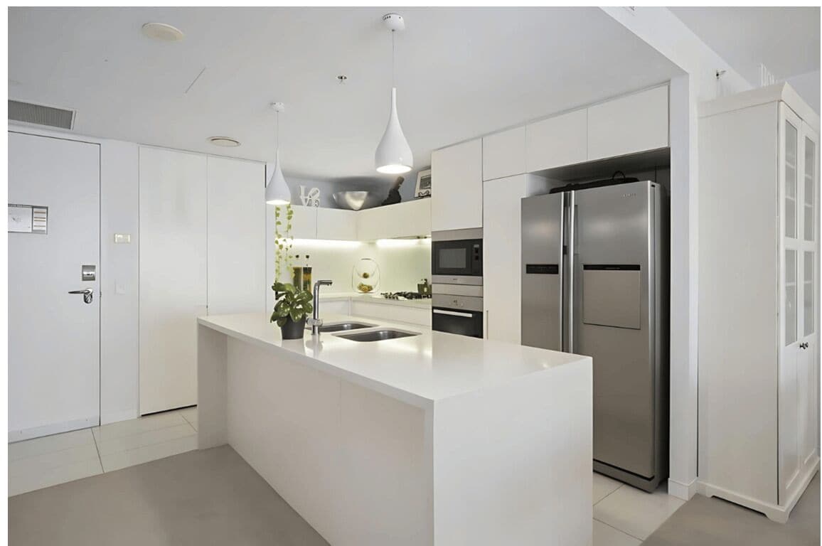 A modern kitchen with a central island, stainless steel appliances, and white cabinetry.