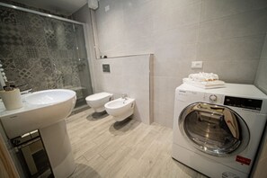 A modern bathroom with a sink, bidet, toilet, and a front-loading washing machine. - [New Open Space] WiFi • SmartTV • Sea at 2 minutes (Varazze)