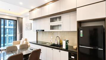 Una cocina moderna con un refrigerador negro, gabinetes blancos y un comedor con dos sillas y una mesa.