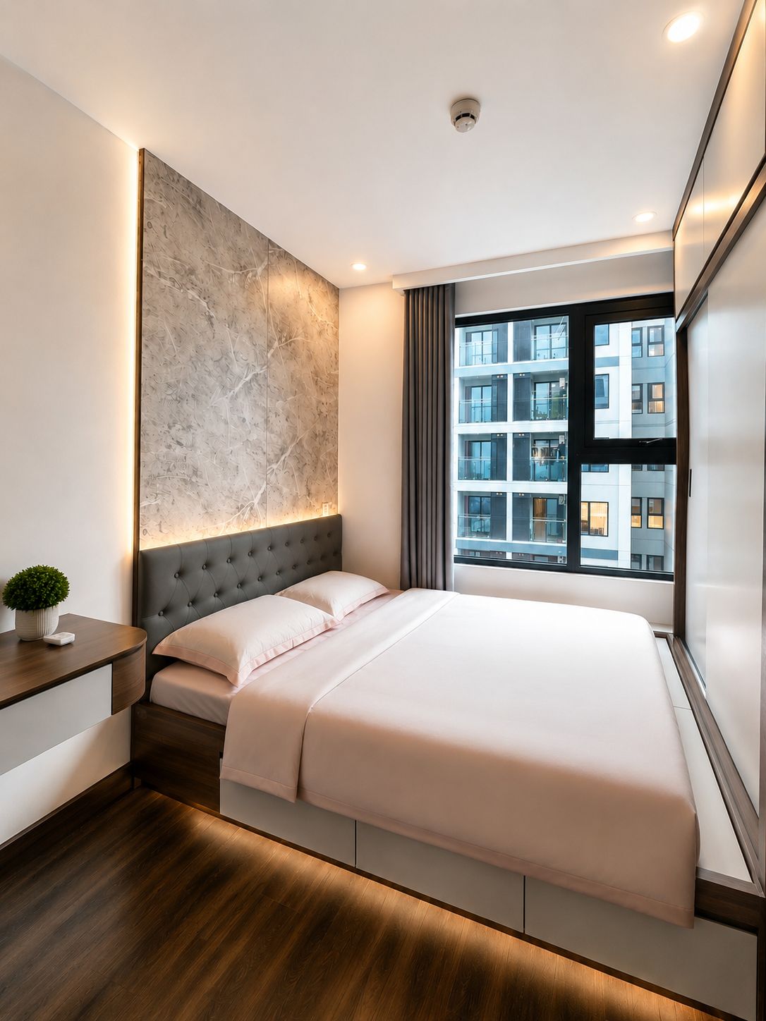 Habitación de hotel moderna con una cama grande, una mesita de noche, una obra de arte en la pared y una ventana con vistas a la ciudad.