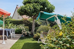 Un jardin avec une table et des chaises, un arbre et une maison en arriĂšre-plan.