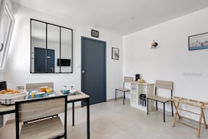 Un espace repas moderne, amĂ©nagĂ© pour le petit-dĂ©jeuner, avec un miroir, une porte et une petite table accompagnĂ©e dâune chaise.