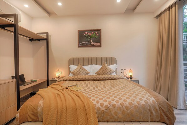 A bedroom with a bed, bedside tables, a desk, a hanging chair, and a painting on the wall.